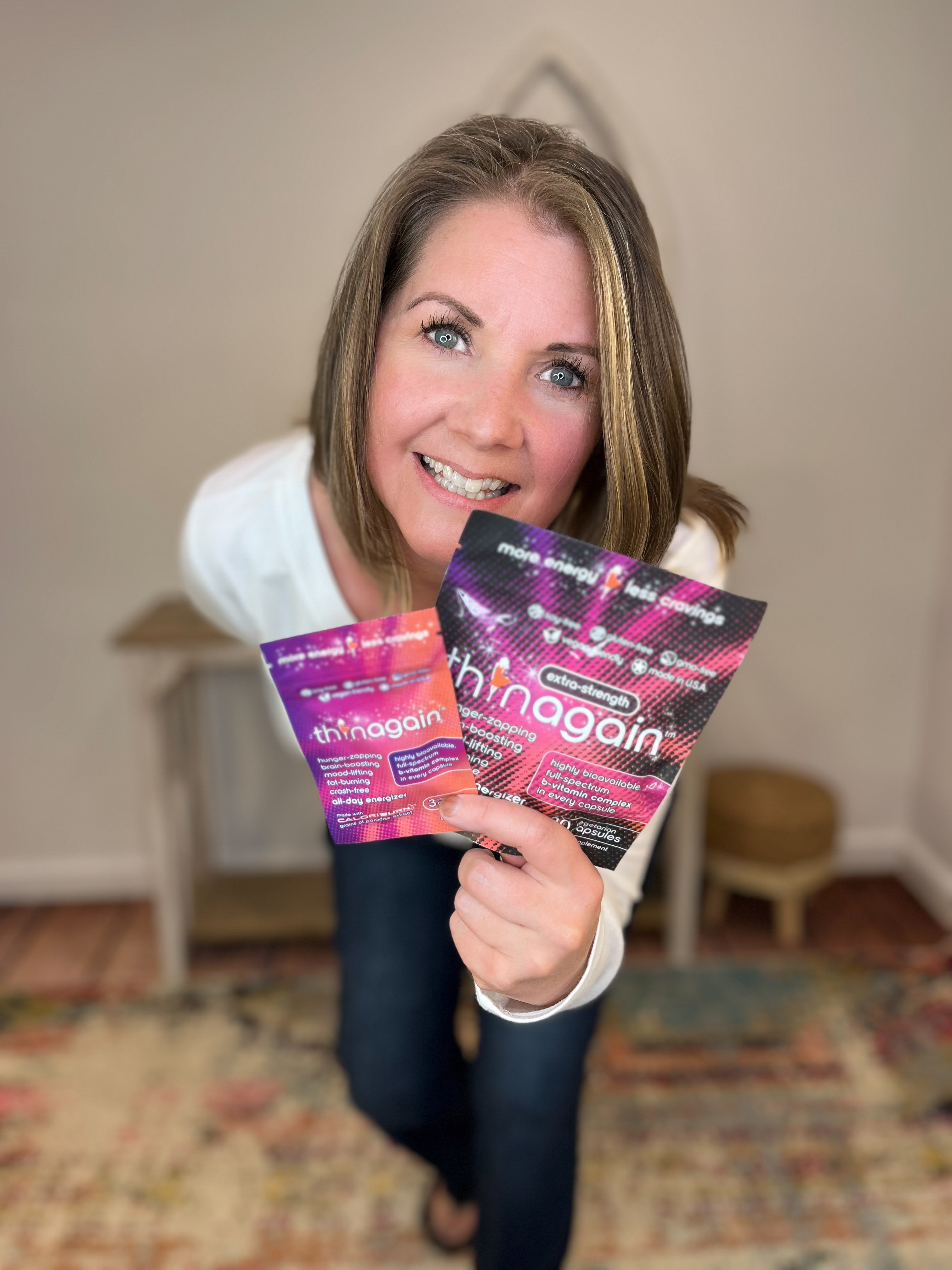 Woman holding two Thinagain products in a room with a blurred background