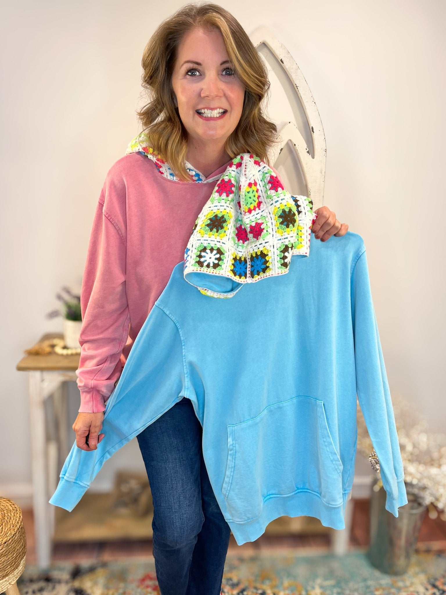Woman wearing Crochet Vintage Wash Pullover Hoodie with a stylish, vintage wash and cozy fit and holding the other colors available in this pullover hoodie.
